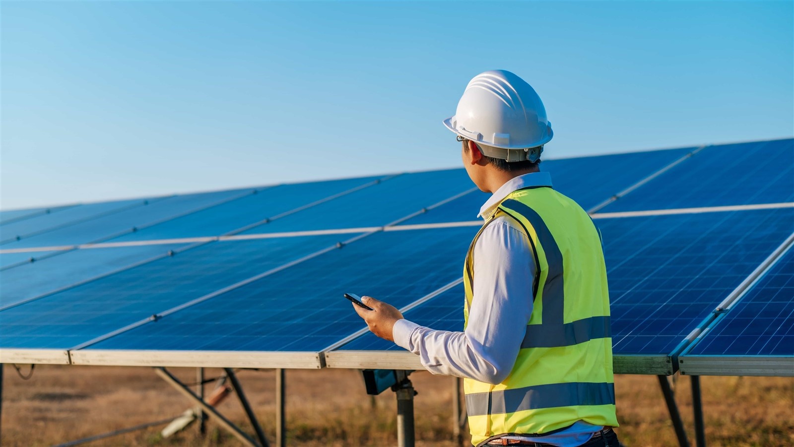 young-asian-technician-man-standing-talking-smartphone-long-rows-photovoltaic-solar-panels-copy-space